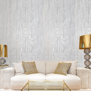 May include: A white sofa with two pillows, a gold coffee table, and two gold lamps against a textured silver wall.