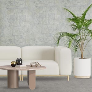 May include: A white sofa with a round coffee table in front of it. The coffee table has a light brown top and two brown legs. There is a small gold sculpture on the table. A potted palm tree is in the corner of the room.