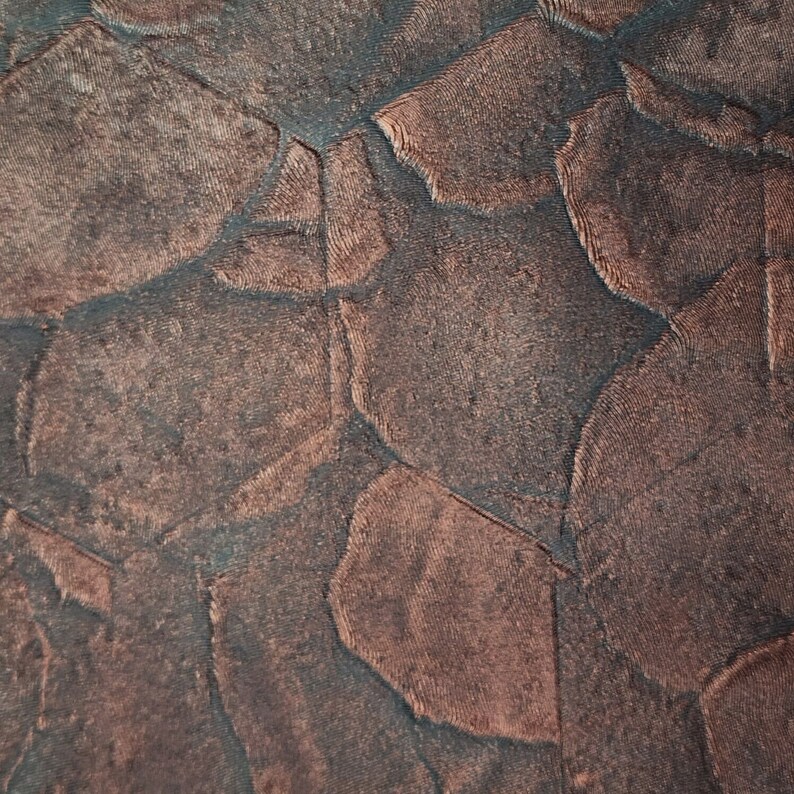 May include: Close-up of a textured fabric with a geometric pattern. The fabric is a dark brown colour with a subtle sheen.