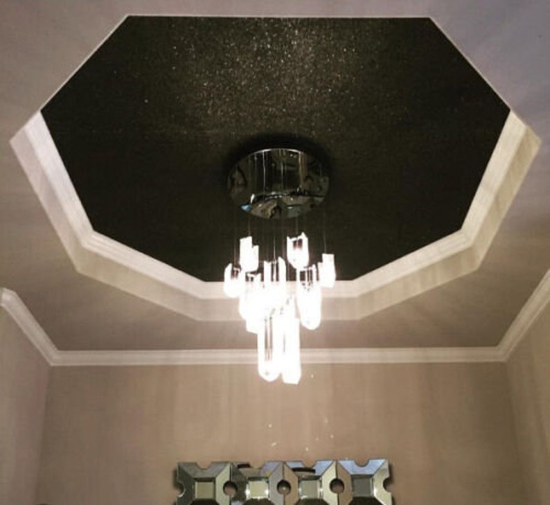 May include: A black ceiling with glitter, a white trim, and a crystal chandelier hanging from the center.
