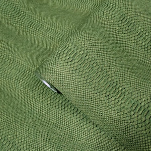 May include: Green faux snakeskin fabric with a textured, scaly pattern. The fabric is folded over on itself, creating a wave-like effect.