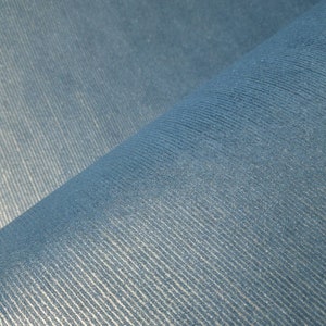 Puede incluir: Primer plano de una tela azul con una superficie texturizada y acanalada. La tela est&aacute; doblada por la mitad, creando una l&iacute;nea diagonal.