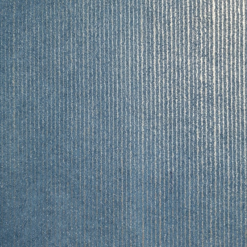 Puede incluir: Primer plano de una tela azul texturizada con rayas plateadas verticales. La tela tiene un brillo sutil.