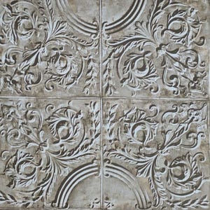 May include: Four square tiles with a repeating ornate floral design. The design features scrolling leaves and flowers in a raised, textured pattern. The color palette is a muted gray with white highlights, creating a vintage or antique aesthetic.