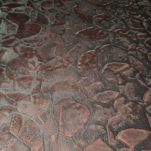 May include: A close-up of a textured fabric with a pattern of irregular, overlapping shapes in shades of brown and grey.