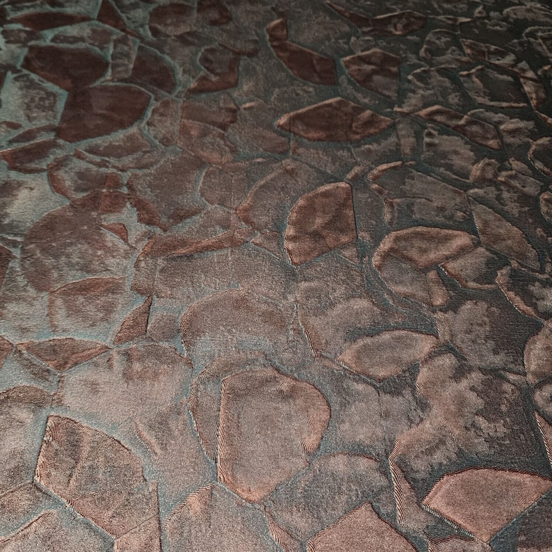 May include: A close-up of a textured fabric with a pattern of irregular, overlapping shapes in shades of brown and grey.
