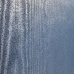 Puede incluir: Primer plano de una tela azul con una sutil textura acanalada vertical. La tela tiene un aspecto ligeramente descolorido, creando una est&eacute;tica vintage.