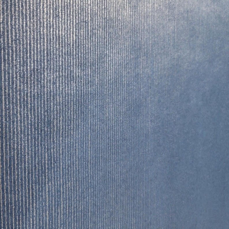 Puede incluir: Primer plano de una tela azul con una sutil textura acanalada vertical. La tela tiene un aspecto ligeramente descolorido, creando una est&eacute;tica vintage.