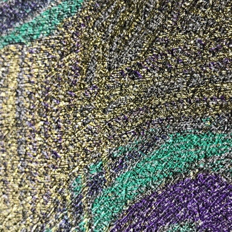 May include: Close-up of a textured surface with a gold, green, and purple color scheme. The surface has a metallic sheen and appears to be made of a fine-grained material.