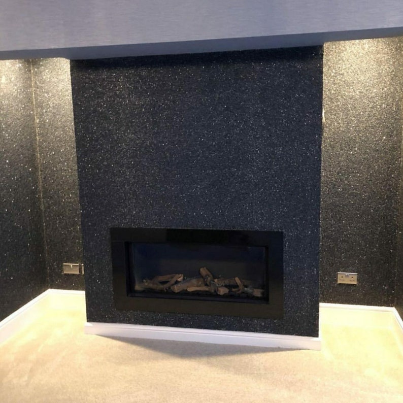 May include: A black fireplace with a black glass firebox and a log set. The fireplace is surrounded by a black glitter wall.