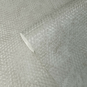 May include: A close-up of a roll of textured wallpaper with a subtle geometric pattern. The wallpaper is a light gray color.