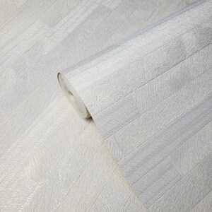 May include: A roll of white wallpaper with a textured, brick-like pattern. The wallpaper has a subtle shimmer.