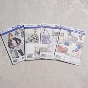 以下が含まれることがあります： 4つのSimplicityソーイングパターンパッケージが表示されており、それぞれにバッグと女性の写真が掲載されています。 パッケージには、Simplicityのロゴが入った青と白のボーダーがあります。 パターンはさまざまなバッグのデザイン用です。