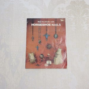 May include: A book titled "How to create with HORSESHOE NAILS" with a red background and images of various jewelry pieces made with horseshoe nails.