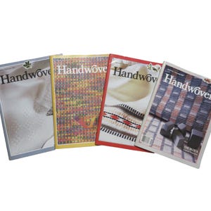 May include: Four copies of "Handwoven" magazine are displayed, each with a different cover design. The covers feature various woven textile patterns in colors like blue, yellow, and red. The magazine titles are in a serif font.