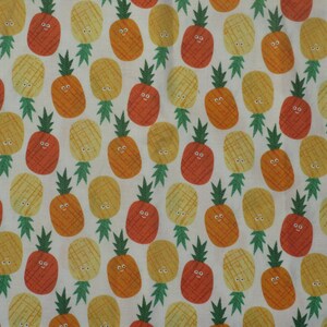 May include: A white fabric with a repeating pattern of cartoon pineapples in shades of yellow, orange, and red. Each pineapple has a smiling face and green leafy top. The design is playful and bright.