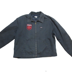 May include: Navy blue jacket with a full zipper closure and a collared neckline. The jacket features a red and white patch on the chest with the text "INDEPENDENT". A small Dickies label is visible. The jacket has two front pockets.