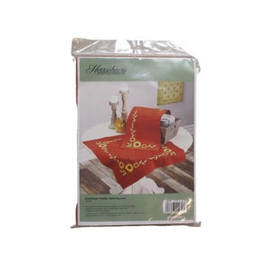 May include: Packaged red table runner with embroidered yellow sunflowers and green leaves. The packaging includes the brand name "Herschner's" and the text "Sunflower Table Table Runner".