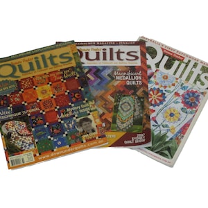 May include: Three quilting magazines are displayed, each showcasing colorful quilt designs. The magazines feature titles like "Quilts" and include text such as "New Technique Tutorial" and "Magnificent Medallion Quilts."