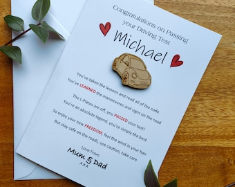 Op de afbeelding: Een witte kaart met rode harten en de tekst "Gefeliciteerd met het halen van je rijbewijs Michael" en een houten uitsnijding van een Volkswagen Kever. De kaart bevat ook de tekst "Je hebt de lessen gevolgd en alle regels gelezen Je hebt de manoeuvres en borden op de weg GELEERD De L-platen zijn eraf, je hebt je examen GEHAALD! Je bent een absolute legende, je bent gewoon de beste Geniet van je nieuwe VRIJHEID, voel de wind in je haar Maar blijf veilig op de weg, wees voorzichtig, pas op jezelf op Liefs van Mama en Papa XXX"