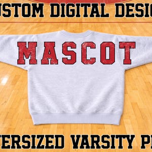 May include: A light gray crewneck sweatshirt featuring the word MASCOT in large, distressed red block letters across the chest. The text CUSTOM DIGITAL DESIGN appears at the top and OVERSIZED VARSITY PNG is at the bottom of the image.