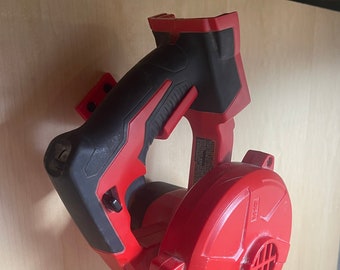 May include: A red and black cordless leaf blower by Milwaukee. The blower is mounted on a wall with a bracket. The blower has a black handle and a red fan.