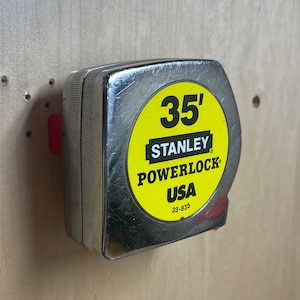 May include: A silver Stanley Powerlock tape measure with a yellow label that reads "35' Stanley Powerlock USA 33-835".