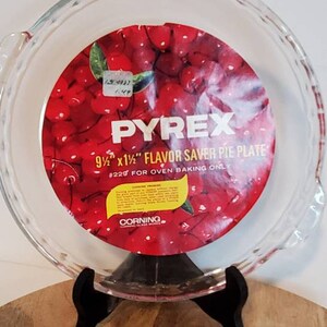 May include: A clear glass 9 1/2 by 1 1/2 inch Pyrex pie plate with a red cherry design. The plate is labeled "Flavor Saver Pie Plate" and "#225 for oven baking only".