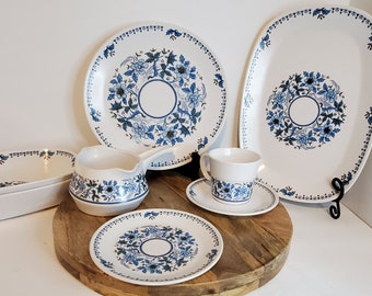 May include: A set of white ceramic dishes with a blue floral pattern. The set includes a large platter, a smaller platter, two oval serving dishes, a creamer, a cup and saucer, and a small plate.