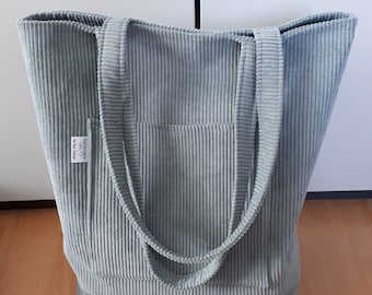 May include: A light gray corduroy tote bag with two handles. The bag has a small pocket on the front with a white label that says "handmade with love".