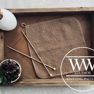 Könnte beinhalten: Ein Holztablett mit einem gewebten braunen Topflappen, Stricknadeln und einer weißen Vase mit Holzspießen. Eine kleine Sukkulentenpflanze in einem weißen Topf befindet sich ebenfalls auf dem Tablett. Das Tablett hat Holzperlengriffe und den Text "WW STUDIOS KNITTING PATTERN".