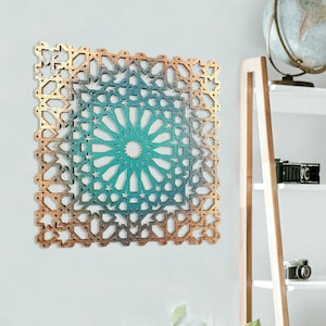 May include: A teal and gold geometric wall art piece with a circular design in the centre. The art is hanging on a white wall in a home office setting.