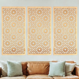 May include: Three gold-coloured metal wall decor panels with a geometric pattern. The panels are hanging on a white wall above a brown leather sofa.