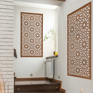 May include: Two brown wooden wall decor panels with intricate geometric patterns, hanging on white walls in a modern home.
