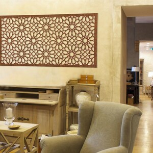 May include: A brown wooden wall decor with a geometric pattern of stars and circles. The decor is hanging on a light beige wall in a living room setting.