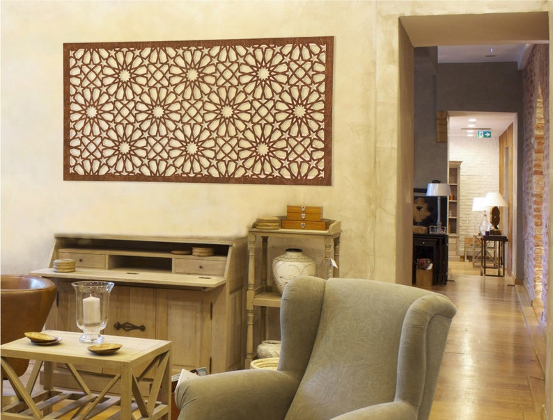May include: A brown wooden wall decor with a geometric pattern of stars and circles. The decor is hanging on a light beige wall in a living room setting.