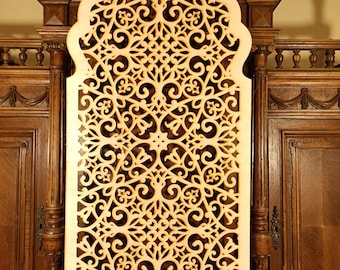 May include: A decorative wooden wall panel with a intricate, laser-cut design featuring a repeating pattern of swirls and floral motifs. The panel is light brown in color and has an arched top.