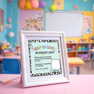 May include: A white framed sign with the text "HELP US HAVE an amazin' year!" in a classroom setting. The sign includes a request for classroom wish list items and a "scan me!" QR code. The background shows a colorful classroom.