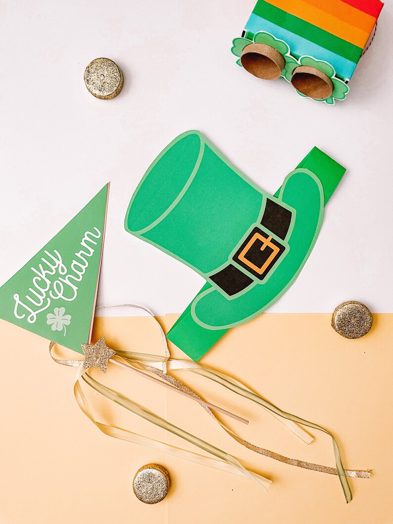 May include: A green leprechaun hat party prop with a black belt and a gold buckle. A green triangle flag with the text "Lucky Charm" and a gold star wand with green and gold ribbons are also included.
