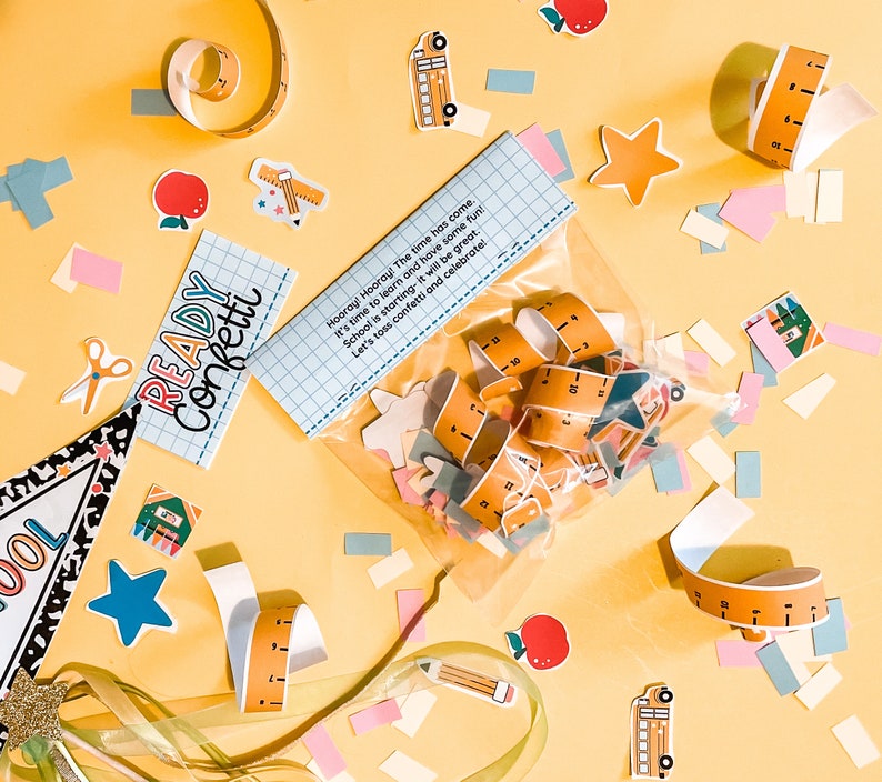 Pode incluir: Um saco de pl&aacute;stico transparente cheio de confete colorido para uma festa de volta &agrave;s aulas. O confete inclui imagens de &ocirc;nibus escolares, r&eacute;guas, estrelas e l&aacute;pis. O saco est&aacute; sobre uma superf&iacute;cie amarela com uma placa que diz "Pronto Confete!" e o texto "Viva! Viva! Chegou a hora. &Eacute; hora de aprender e se divertir! A escola come&ccedil;a, ser&aacute; &oacute;timo. Vamos jogar confete e celebrar!"