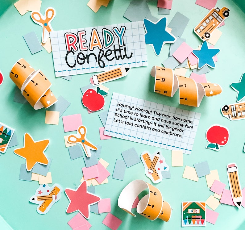 May include: A colorful confetti party kit with a sign that says "Ready Confetti!"  The kit includes a variety of confetti pieces, including stars, pencils, rulers, and school buses. The sign is on a light blue background.