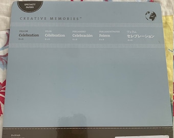 Puede incluir: Un paquete de hojas de vitela de 20,3 x 20,3 cm para manualidades. El paquete es azul y presenta el texto "Creative Memories" y "Vellum Celebration" en blanco. El paquete también incluye el texto "New" y un código de barras.