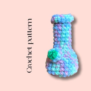 May include: A crocheted light blue, green, and purple bong with a green flower detail.