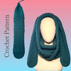 May include: Teal crochet bunny ear cowl and matching long piece. The cowl is displayed on a mannequin head. The text "Crochet Pattern" is on the left side of the image. The cowl has a neck warmer and two long ear-shaped pieces.