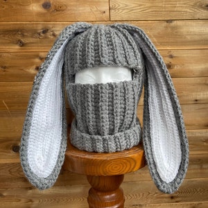May include: Gray crocheted bunny hat with long white ears. The hat has a face mask attached.