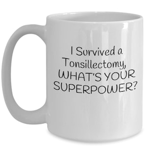 May include: White ceramic coffee mug with a black inscription that reads "I Survived a Tonsillectomy, WHAT'S YOUR SUPERPOWER?"