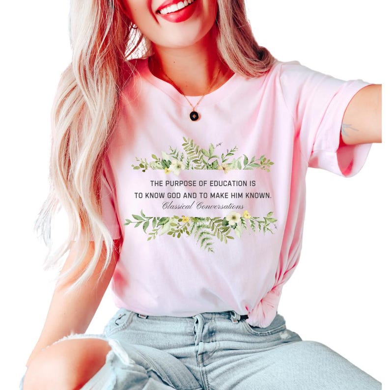 May include: A pink t-shirt with a floral design and the text "THE PURPOSE OF EDUCATION IS TO KNOW GOD AND TO MAKE HIM KNOWN. Classical Conversations".