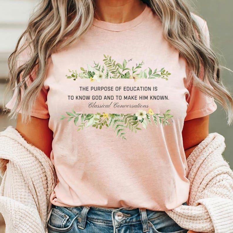 May include: A pink t-shirt with a floral design and the text "THE PURPOSE OF EDUCATION IS TO KNOW GOD AND TO MAKE HIM KNOWN. Classical Conversations".