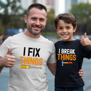 May include: Two people wearing matching t-shirts. One shirt is white with the text "I FIX THINGS" and a yellow screwdriver graphic. The other shirt is black with the text "I BREAK THINGS" and a hammer graphic.