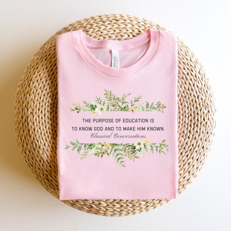 May include: Pink t-shirt with a floral design and the text "THE PURPOSE OF EDUCATION IS TO KNOW GOD AND TO MAKE HIM KNOWN. Classical Conversations".